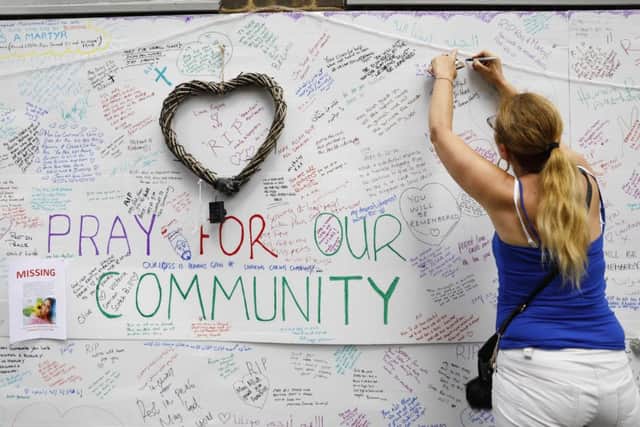 Wellwishers write messages on a wall of condolence following the blaze at Grenfell Tower. Picture: Getty Images