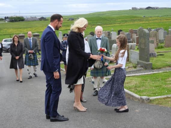 Flower girl Josie Gibbon, nine, presents a posy to Crown Princess Mette Marit of Norway, accompanied by the Crown Prince Haakon. The Norwegian royals were visiting the St Magnus festival
