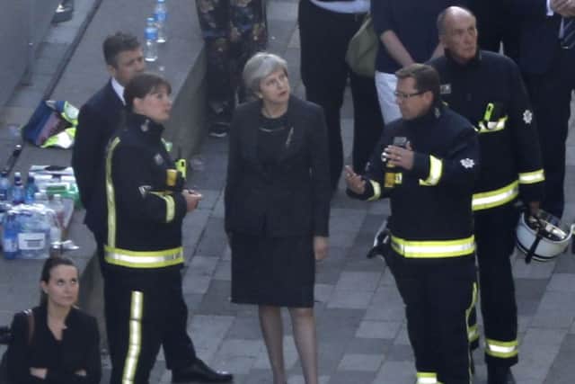 Theresa May meets firefighters as she visits the remains of Grenfell Tower in west London. The prime minister is facing mounting criticism over her handling of the disaster. Picture: Tolga Akmen/AFP/Getty