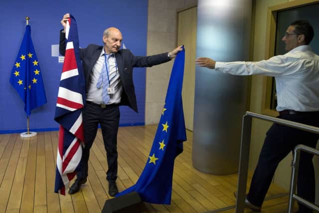 A member of protocol changes the EU and British flags prior to the start of Brexit negotiations. Picture: AP/Virginia Mayo