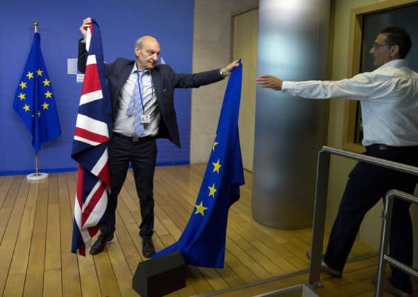 A member of protocol changes the EU and British flags prior to the start of Brexit negotiations. Picture: AP/Virginia Mayo