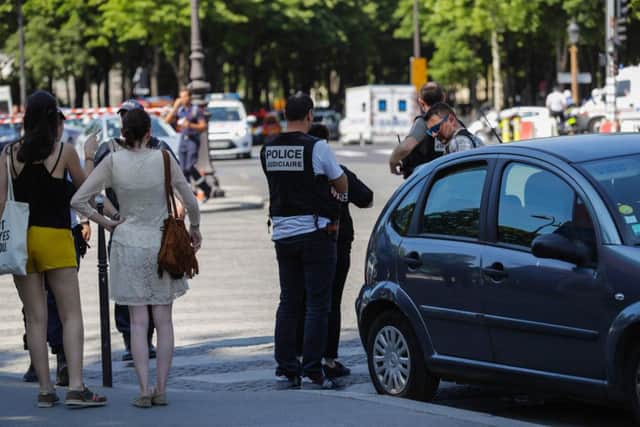 Police officers and pedestrians stand by a sealed off area on the Champs-Elysees avenue in Paris. Picture: Thomas Samson/AFP/Getty