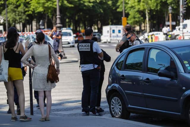 Police officers and pedestrians stand by a sealed off area on the Champs-Elysees avenue in Paris. Picture: Thomas Samson/AFP/Getty