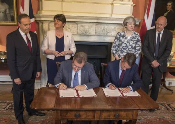 DUP MP Jeffrey Donaldson and Tory Chief Whip Gavin Williamson sign the deal in Downing Street watched by Arlene Foster, her deputy Nigel Dodds, Theresa May and First Secretary of State Damian Green. Picture: Getty