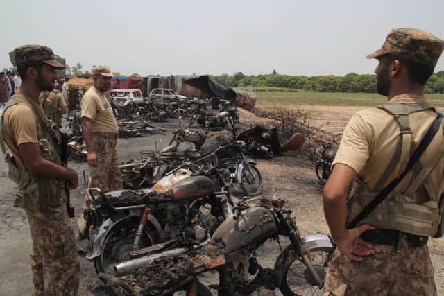 Pakistani soldiers stand guard beside burnt out vehicles at the scene. Picture: AFP/Getty Images
