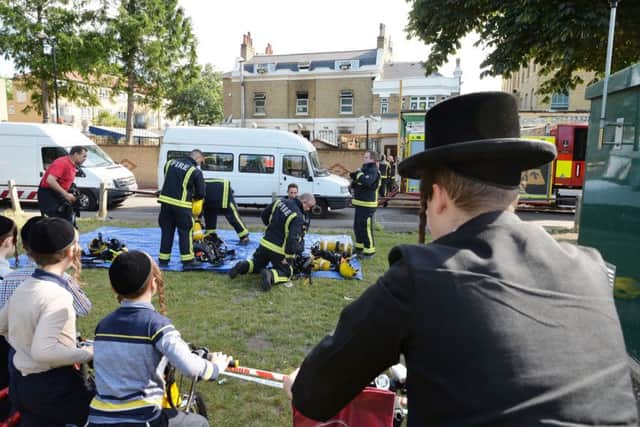 Members of the public watch on as fire crews gather outside the school in Craven Walk in Hackney. Picture: PA