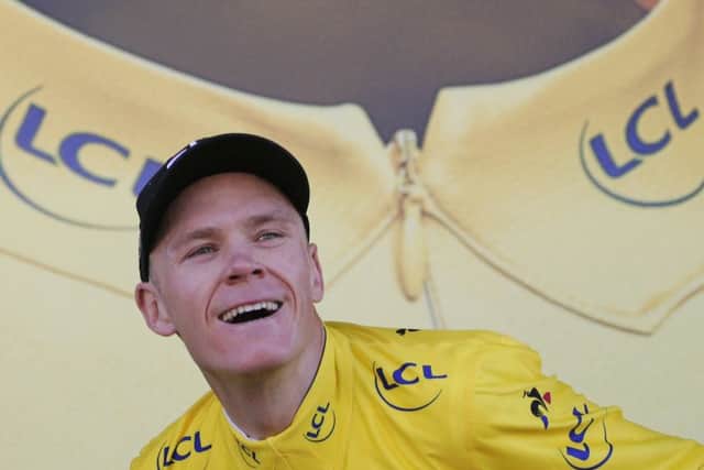 Britain's Chris Froome, wearing the overall leader's yellow jersey, prepares to throw his bouquet of flowers to cheering fans on the podium. Picture: Christophe Ena/AP