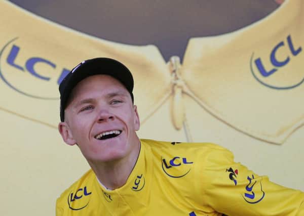 Britain's Chris Froome, wearing the overall leader's yellow jersey, prepares to throw his bouquet of flowers to cheering fans on the podium. Picture: Christophe Ena/AP