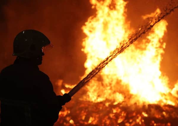 Firefighters douse nearby buildings as a bonfire is lit in Albertbridge Road, Belfast. Picture: PA Wire