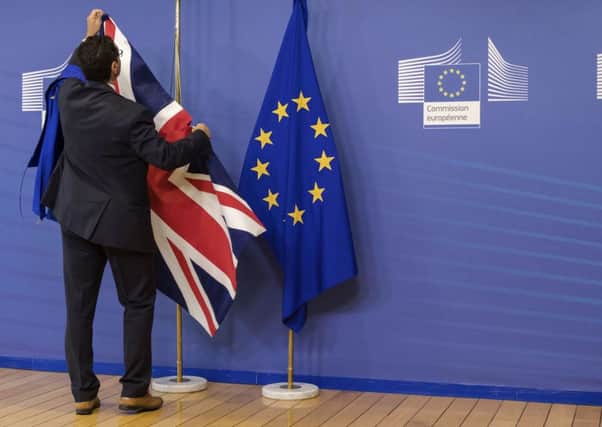 A protocol member adjusts a British flag prior to a meeting between EU chief Brexit negotiator Michel Barnier and British Secretary of State David Davis in Brussels. Picture: AP/Geert Vanden Wijngaert