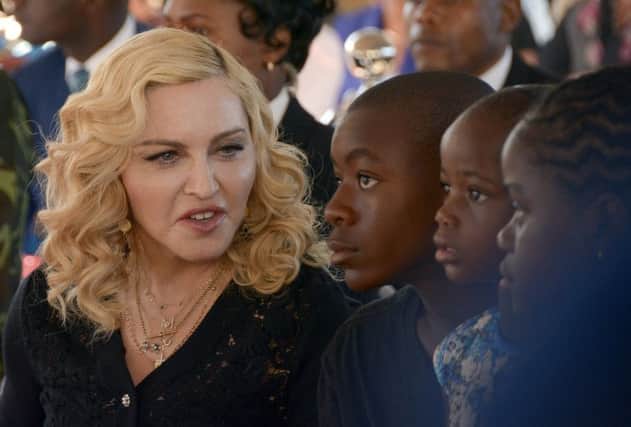 FILE- In this July 11, 2017 file photo, Madonna, left, sits with her adopted children David, Stella and Mercy, at the opening of The Mercy James Institute for Pediatric Surgery and Intensive Care, located at the Queen Elizabeth Central Hospital in the city of Blantyre, Malawi. A lawyer for Madonna said Thursday July 27, 2017, that the star and her twin daughters Stella and Estere have accepted damages form the publisher of the Mail Online website over an article that was a "serious invasion of privacy." Madonna sued Associated Newspapers over a January story giving details of her adoption of the 4-year-old twins from Malawi.  (AP Photo Thoko Chikondi, File)