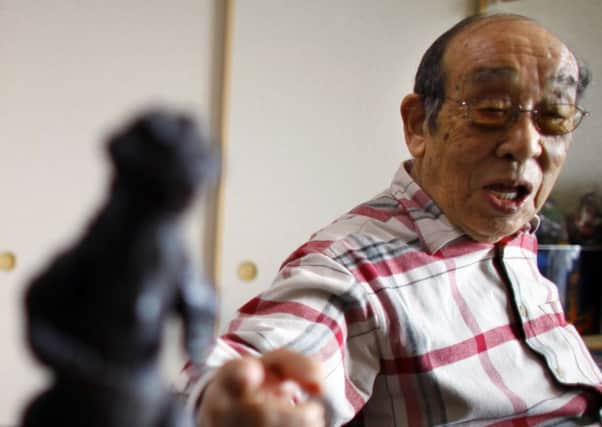 Original Godzilla actor Haruo Nakajima points to a figure of the monster. He has died at the age of 88. Picture: AP