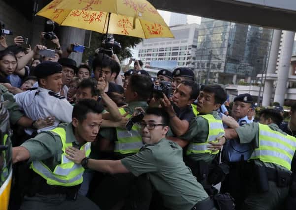 Officers try to clear the way for a prison bus carrying Hong Kong activist Joshua Wong at the high court after sentencing in Hong Kong. Picture: AP Photo/Vincent Yu