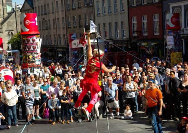 Crowds gather in the street to watch a festival performer in a typical August scene in Edinburgh.