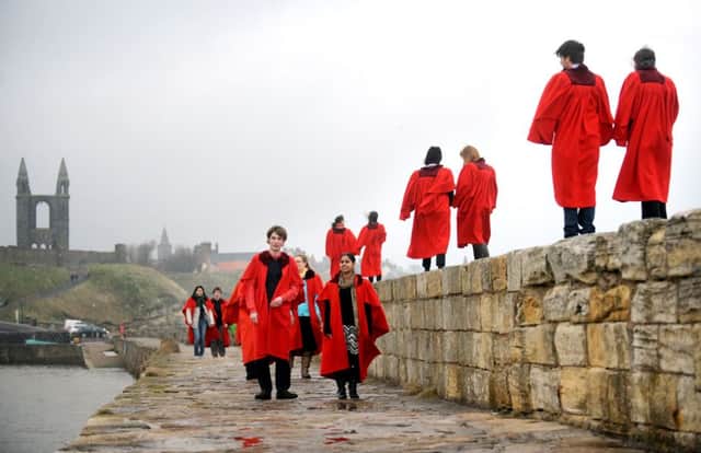 Students from the University of St Andrews walk along the harbour wall wearing their famous red gowns. Picture: Jane Barlow