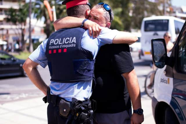 A man embraces a police officer on the spot where five terrorists were shot by police on August 18, 2017 in Cambrils, Spain. . (Photo by Alex Caparros/Getty Images)