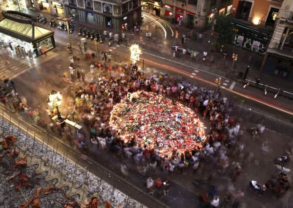 People pay respect at a memorial tribute of flowers, messages and candles to the victims on Barcelona's historic Las Ramblas promenade. Picture: AP Photo/Manu Fernandez