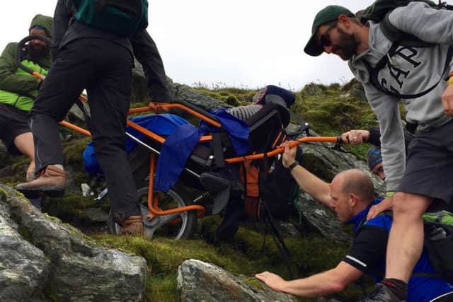 Volunteers get Alex to the summit of Ben Lomond. Picture: SWNS