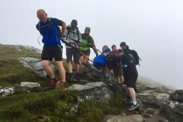Volunteers carry Alex up to the top of Ben Lomond. Picture: SWNS