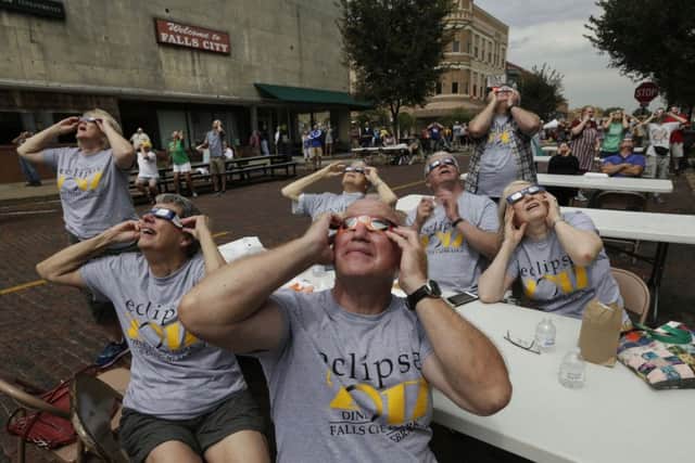 The sun peeks through the clouds as people wearing solar glasses watch the eclipse in Falls City, Neb., Monday, Aug. 21, 2017. (AP Photo/Nati Harnik)