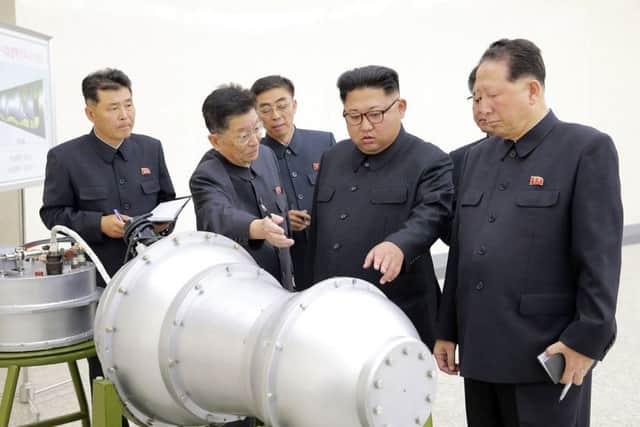 North Korean leader Kim Jong-Un (C) looking at a metal casing with two bulges at an undisclosed location. Picture: AFP PHOTO/KCNA VIA KNS