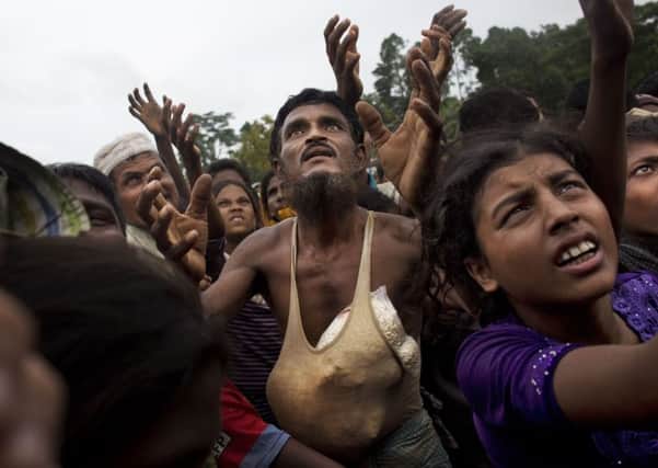 A Rohingya man stretches his arms out for food distributed by local volunteers. Picture: AP Photo/Bernat Armangue