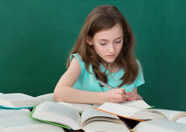 Girl With Many Open Books At Desk In Classroom