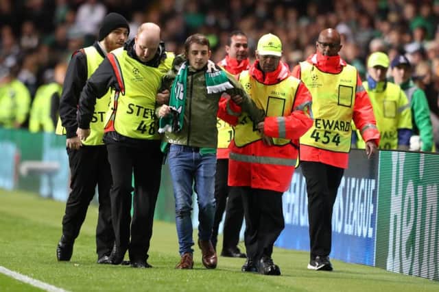A fan is led off after running on the pitch and allegedly confronting Kylian Mbappe. Picture: Andrew Milligan/PA Wire