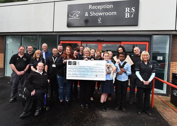 Audrey McJimpsey, training manager at RSBi, and RSBi staff hold up a cheque for £2,300 raised by the sports fun day. Picture: Contributed