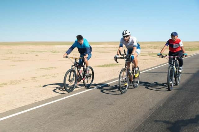 Day 24  Children cycle with Mark Beaumont on part of his journey through the Gobi desert.  Picture: SWNS
