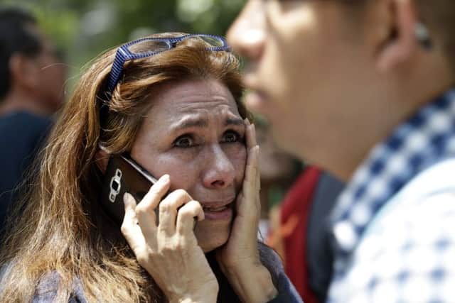 A woman tries to reach people on her mobile phone after she evacuated with others to Paseo de la Reforma Avenue. Picture: AP