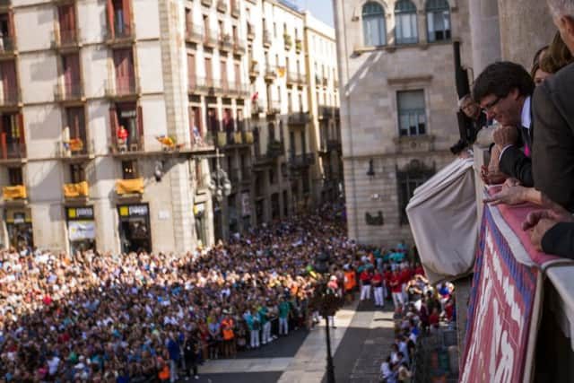 The President of the government of Catalonia, Carles Puigdemont, looks at the crown as he stands at the balcony of the city hall building in Barcelona. (AP Photo/Emilio Morenatti)