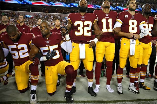 Samaje Perine (32) and Chris Carter (55) of the Washington Redskins hold hands as they stand and kneel in unison during the national anthem before playing against the Oakland Raiders. Picture: Patrick Smith/Getty Images