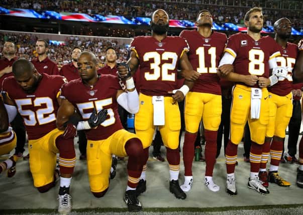 Samaje Perine (32) and Chris Carter (55) of the Washington Redskins hold hands as they stand and kneel in unison during the national anthem before playing against the Oakland Raiders. Picture: Patrick Smith/Getty Images