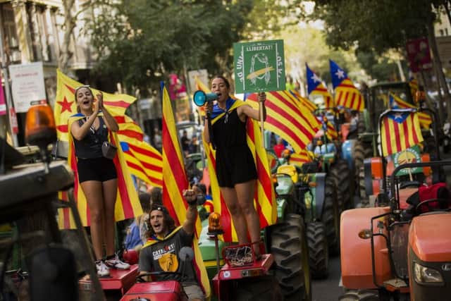 People with the estelada, or independence flags, shout slogans on top of parked tractors during a protest by farmers in Barcelona.