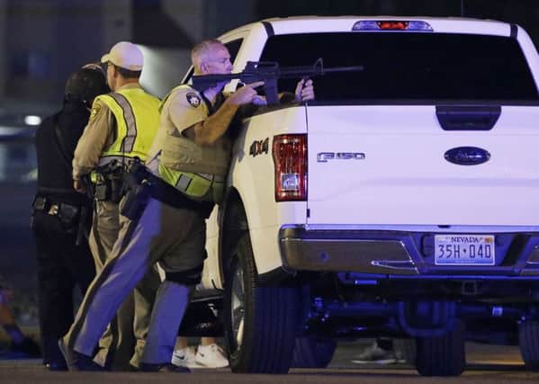 A police officer takes cover behind a truck at the scene of a shooting in Las Vegas, where over 50 were killed and over 500 injured.