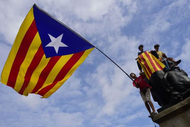 Protesters wave a giant Catalan pro-independence 'Estelada' flag atop a sculpture during a demonstration in Barcelona. Picture: AFP/Getty Images