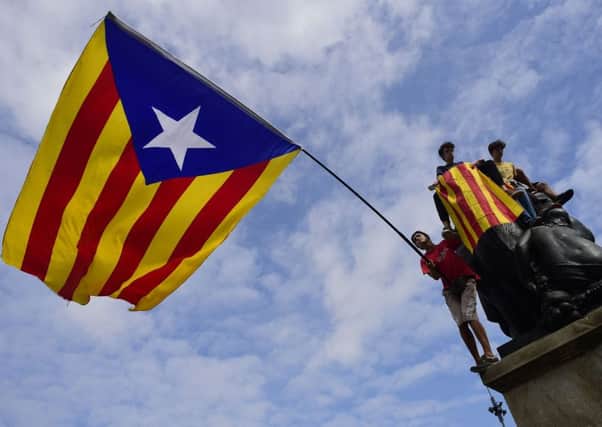 Protesters wave a giant Catalan pro-independence 'Estelada' flag atop a sculpture during a demonstration in Barcelona. Picture: AFP/Getty Images