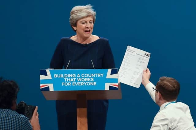 Lee Nelson gives a piece of paper written as a mock P45 to Theresa May during her speech. Picture: AFP/Getty Images