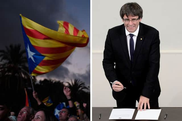 Supporters of an independence for Catalonia listen to Catalan president Carles Puigdemont, right, as his  speech is broadcast on a television screen at the Arc de Triomf. Picture: Getty