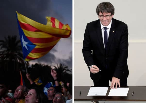 Supporters of an independence for Catalonia listen to Catalan president Carles Puigdemont, right, as his speech is broadcast on a television screen at the Arc de Triomf. Picture: Getty