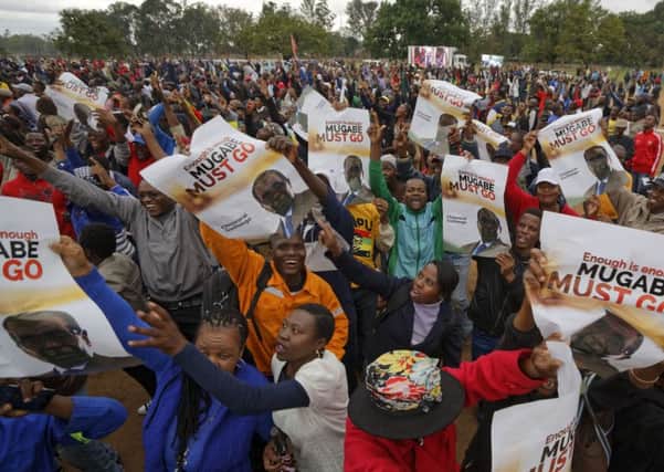 Protesters hold posters asking President Mugabe to step down. Picture; AP