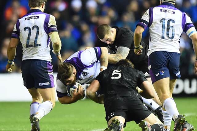 Scotland's Jamie Bhatti, centre, is tackled during the game against the All Blacks. Picture: Andy Buchanan/AFP/Getty