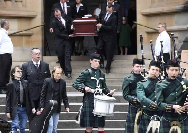 Angus Young, the brother of Malcolm Young, front centre, carries a guitar as he leads the casket of his brother Malcolm Young, AC/DC co-founder and guitarist, from St. Mary's Cathedral in Sydney. Picture: AP