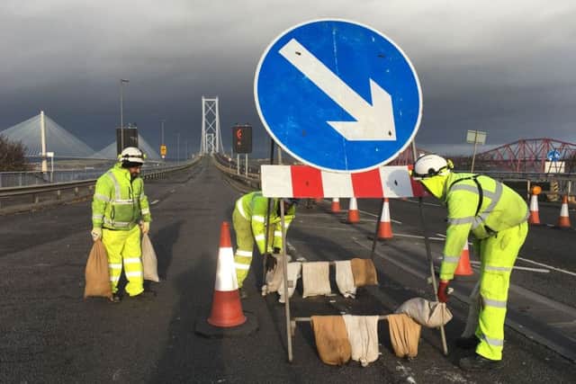 Workers on the Forth Bridge putting sandbags on a sign to weigh it down. Picture: PA