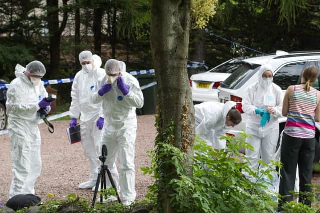 Police officers gather evidence at the scene of the shooting in Ratho