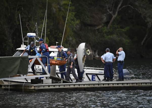Emergency workers carry to shore what is believed to be a body and debris from a seaplane that crashed into the Hawkesbury River, north of Sydney, Australia, Sunday, Dec. 31, 2017. The plane crashed into a river killing all six people on board, officials said. (Perry Duffin/AAP Image via AP)
