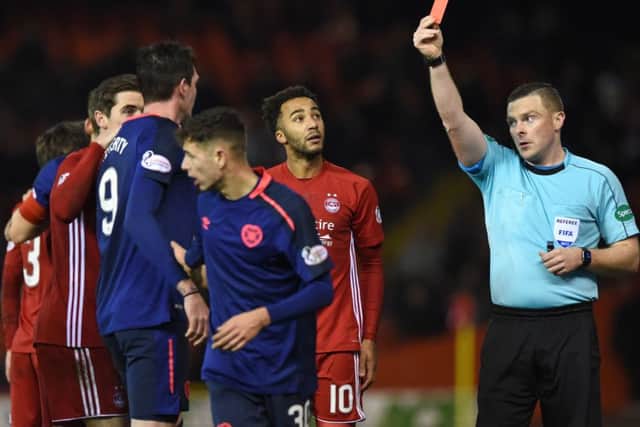 Referee John Beaton shows a red card to Hearts Kyle Lafferty following his scything tackle on Aberdeens Graeme Shinnie. Picture: SNS.