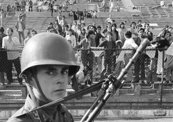 A soldier guards prisoners at Chile's National Stadium in 1973, shortly after the country endured a violent political coup. Picture: Bettmann Archive