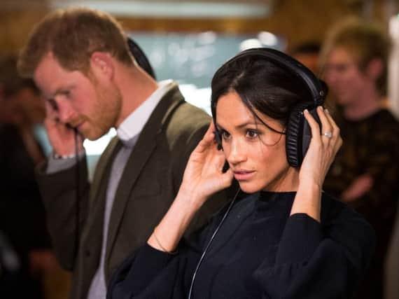 Britain's Prince Harry and his fiancÃ©e, US actress Meghan Markle, listen to a broadcast through headphones during a visit to Reprezent 107.3FM community radio station in Brixton. Picture: Getty Images
